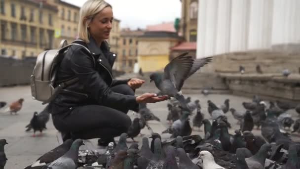 Красивая молодая женщина кормит голубей на улице — стоковое видео