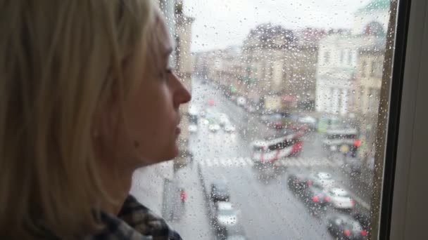 Jeune fille regardant par la fenêtre un jour de pluie — Video