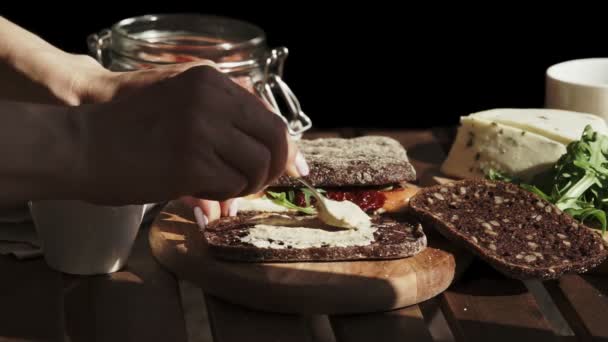 Female hand making sandwich with hummus and salmon for breakfast. Close-up. Sunny day — Stock Video