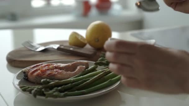 La hembra vierte la salsa sobre los filetes de salmón con espárragos — Vídeos de Stock