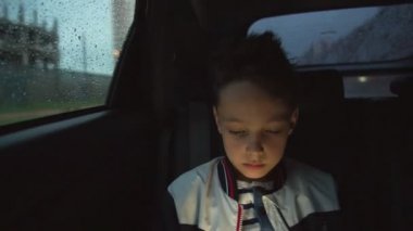 Yağmurlu havalarda arabanın içinden üzgün çocuk