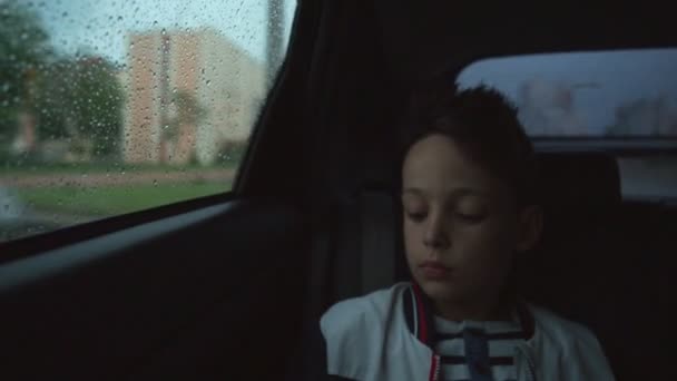 Chico triste dentro de un coche en tiempo lluvioso — Vídeo de stock