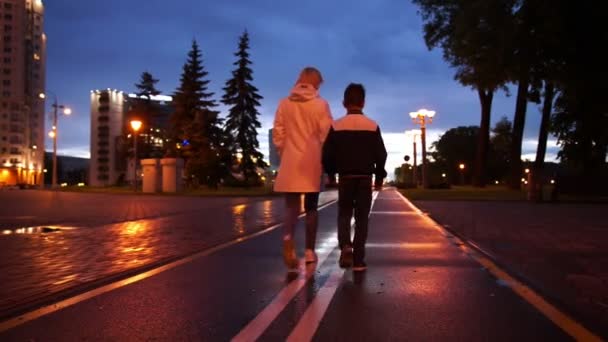 Jovem mulher e menino andando depois da chuva à noite — Vídeo de Stock