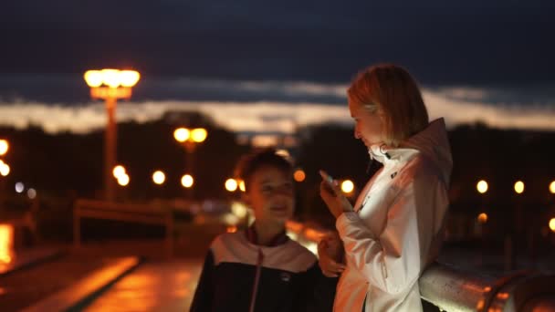 Joven mujer y niño caminando después de la lluvia por la noche — Vídeo de stock