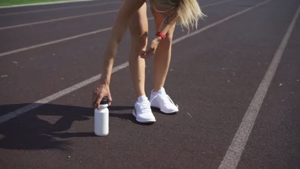 Deportiva chica en pantalones cortos ata los cordones en un zapato blanco — Vídeos de Stock