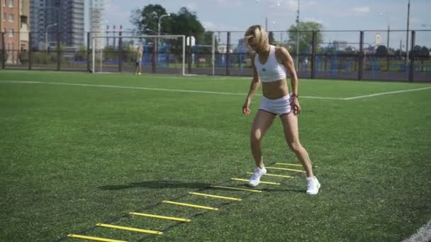 Спортивная девушка делает упражнения на стремянке — стоковое видео