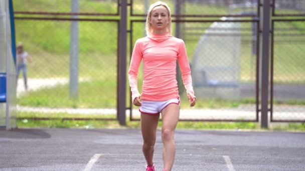 Volwassen fitness vrouw doen lunges met een sprong op een sportveld — Stockvideo