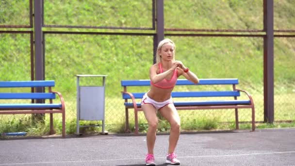 Adult fitness woman doing lunges with a jump on a sports ground — Stock Footage Adult fitness woman doing lunges with a jump on a sports ground Royalty Free Stock Video