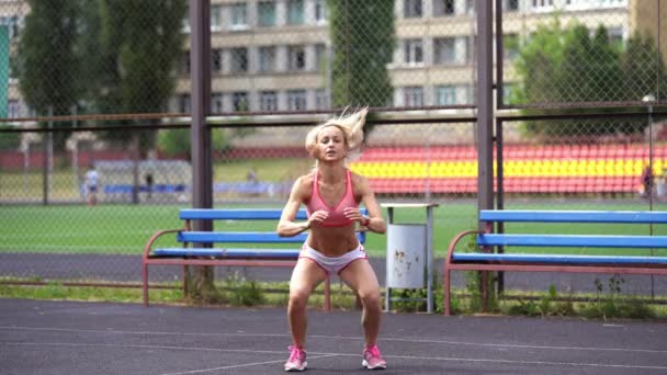 Adult fitness woman doing lunges with a jump on a sports ground — Stock Video
