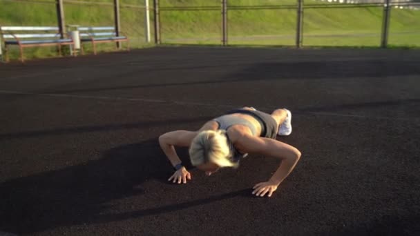 Szczupła kobieta robi push up ćwiczenia na boisko sportowe — Wideo stockowe