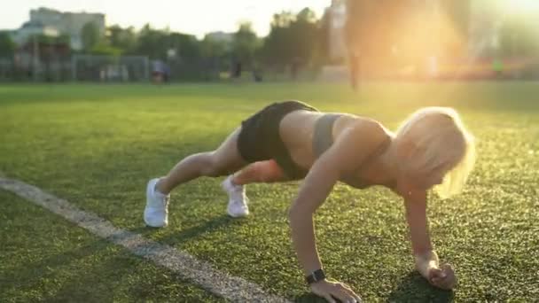 フットボール フィールドで腹筋のエクササイズを行うフィットネス女性筋力トレーニング — ストック動画
