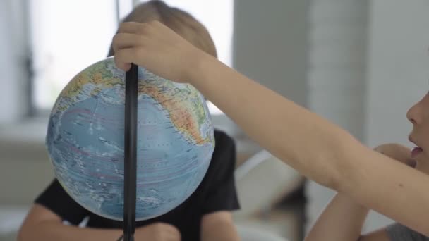 Två vita pojkar snurra en globe och drömmer om resor. — Stockvideo