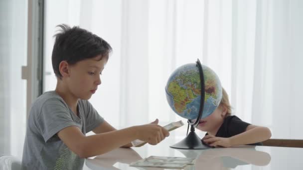 Two caucasian boys spin counting money for travel — Stock Video