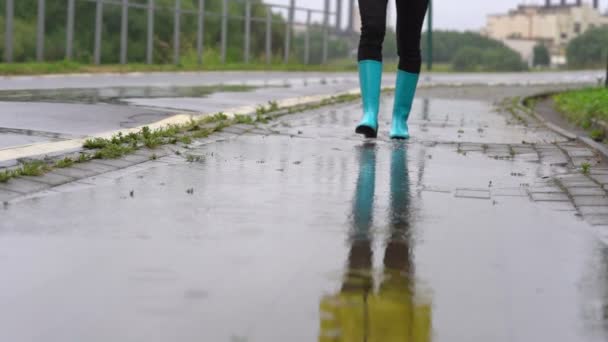 Close-up van vrouw in blauw rubber laarzen springen op de plas — Stockvideo