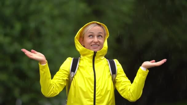 Junge schöne, glückliche Frau in gelbem Regenmantel genießt den Regen. — Stockvideo