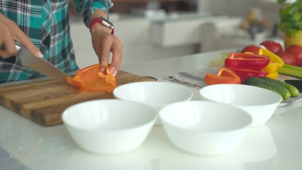 Frauenhände schneiden Paprika in Scheiben auf einem hölzernen Schneidekonzept für gesunde Ernährung. — Stockvideo