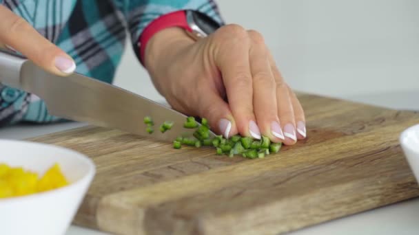 Frauenhände schneiden Paprika in Scheiben auf einem hölzernen Schneidekonzept für gesunde Ernährung. — Stockvideo