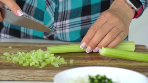 Zenske ruce krájení celer na dřevěné krájecí. — Stock video