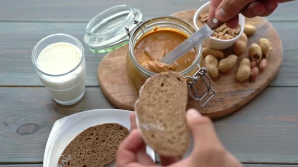 Close-up van mannenhand boterham met pindakaas maken — Stockvideo
