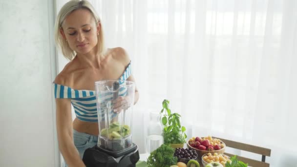 En kvinne som lager grønn grønnsakssmoothie med blender. Sunn spising livsstil – stockvideo