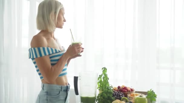 在厨房喝绿色蔬菜奶昔的女人。健康饮食习惯 — 图库视频影像