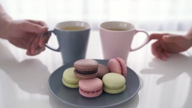 Erkek ve kadın el bardak kahve macaroons ile masaya tutuyorsun yakın çekim