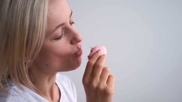 Close up de mulher caucasiana mordendo macaroons coloridos no fundo branco — Vídeo de Stock