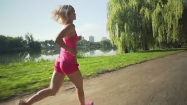 Jonge Kaukasische vrouw joggen in openbaar park in de buurt van de rivier — Stockvideo