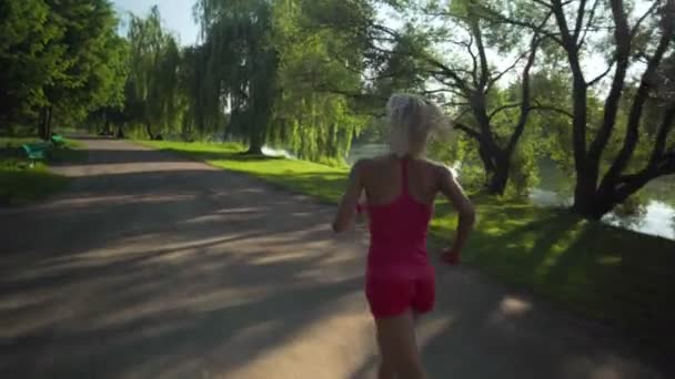 Unga kaukasiska kvinna jogging i offentlig park nära floden — Stockvideo
