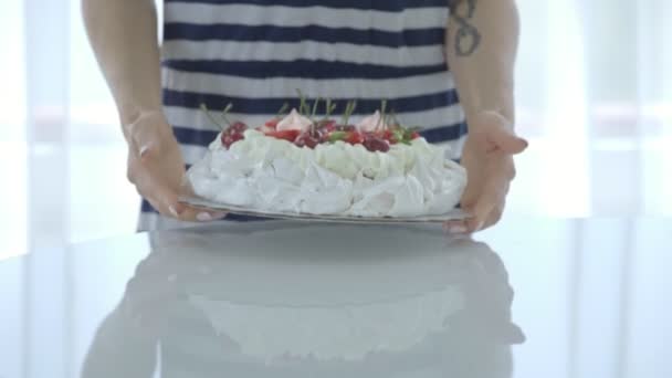 Frau putzt weißen Kuchen mit Beeren am Tisch. pavlov s dessert — Stockvideo