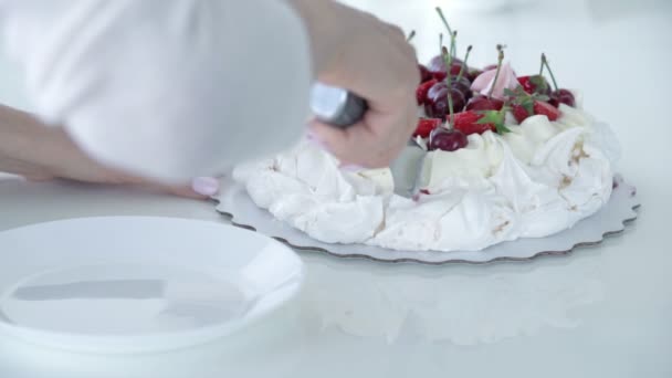 Sobremesa feminina para cortar a mão. Bolo branco com bagas. Sobremesa de Pavlov — Vídeo de Stock