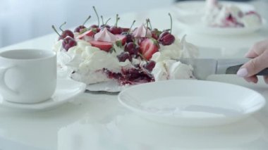 Tatlı kesme ve beyaz plaka koymak el. Çilek beyaz pasta. Pavlov s tatlı