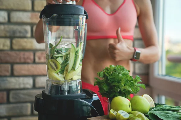 Närbild av ung kvinna med mixer och gröna grönsaker gör detox shake eller smoothie hemma — Stockfoto