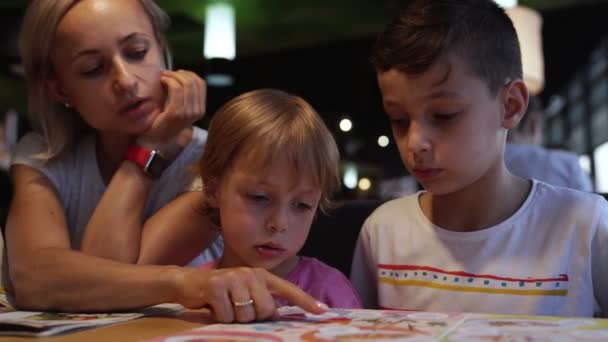 Мама с детьми выбирает пиццу в кафе и веселится — стоковое видео