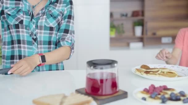 Moeder koken pannenkoeken. Boy is het stelen van pannenkoeken van plaat. — Stockvideo