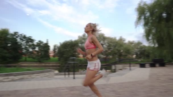 Πορτρέτο του όμορφος γυναίκα που τρέχει μέσω του πάρκου το πρωί κατά την Ανατολή του ηλίου — Αρχείο Βίντεο