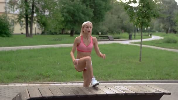 Jeune femme faisant de l'exercice dans le parc sur un banc — Video