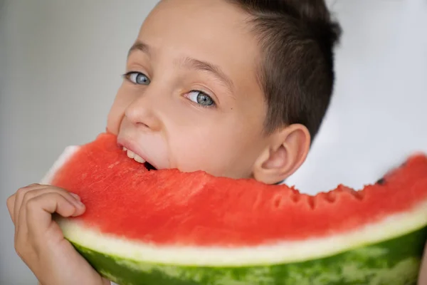 Kavkazská chlapce s výrazné oči, a kousla šťavnatý meloun — Stock fotografie
