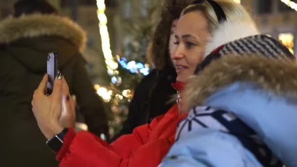 Mujer joven y dos niños se toman selfie en la plaza cerca del árbol de Navidad — Vídeo de stock