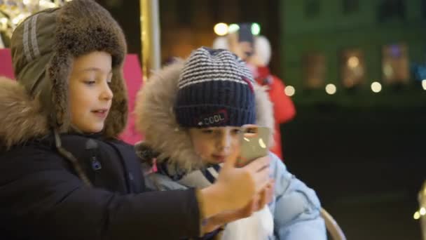 Dva chlapci se selfie na náměstí u vánočního stromu — Stock video