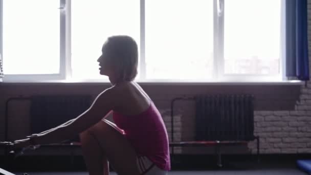 Молодая спортсменка занимается гребными тренажерами в спортзале — стоковое видео