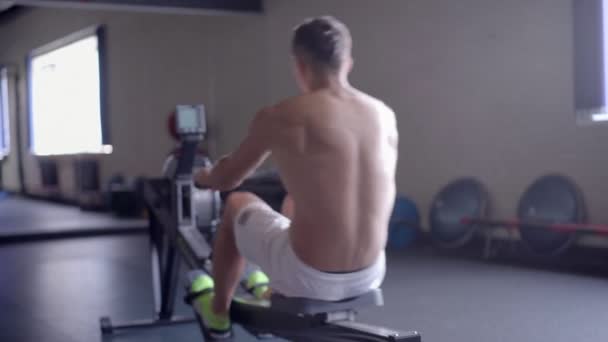 Νέος Αθλητικός άνδρας κάνει προπόνηση Κωπηλατικό μηχάνημα στο γυμναστήριο — Αρχείο Βίντεο