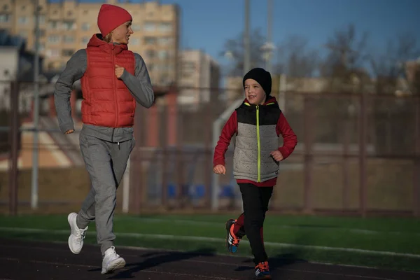 Laufende Frau und Junge. Läufer joggen Laufstrecke. Fitnesstraining für Familien im Freien — Stockfoto