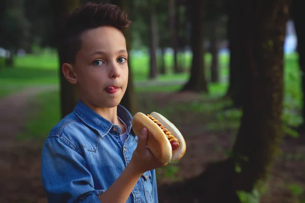 A young boy takes a bite of a hot dog — Stock Photo, Image