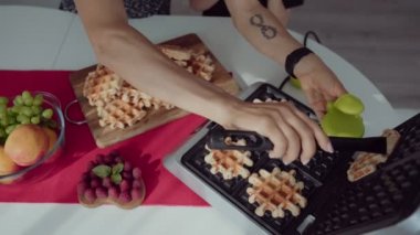 Genç kadın mutfak ve sevimli çocuk waffle yemek ona yardımcı olur