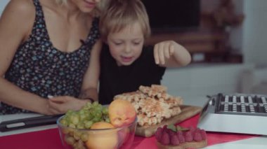 Genç kadın mutfak ve sevimli çocuk waffle yemek ona yardımcı olur