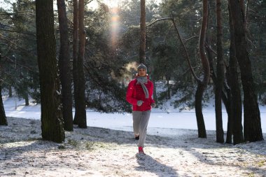 Kadın atlet giyen sıcak giyim çalışan sportif ve eldiven soğuk kış ormanda koşu.