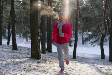 Kadın atlet giyen sıcak giyim çalışan sportif ve eldiven soğuk kış ormanda koşu.