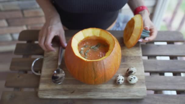 Happy young woman eating pumpkin soup in kitchen — Stock Video