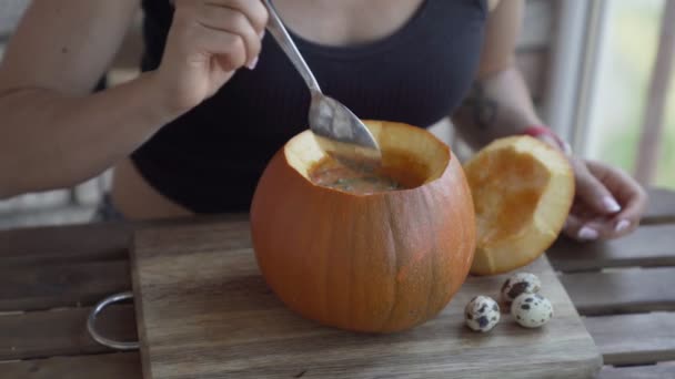 Счастливая молодая женщина ест тыквенный суп на кухне — стоковое видео